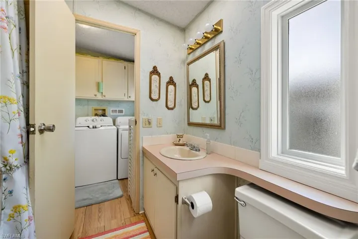 Bathroom featuring washing machine and dryer, vaulted ceiling, toilet, a textured ceiling, and hardwood / wood-style flooring