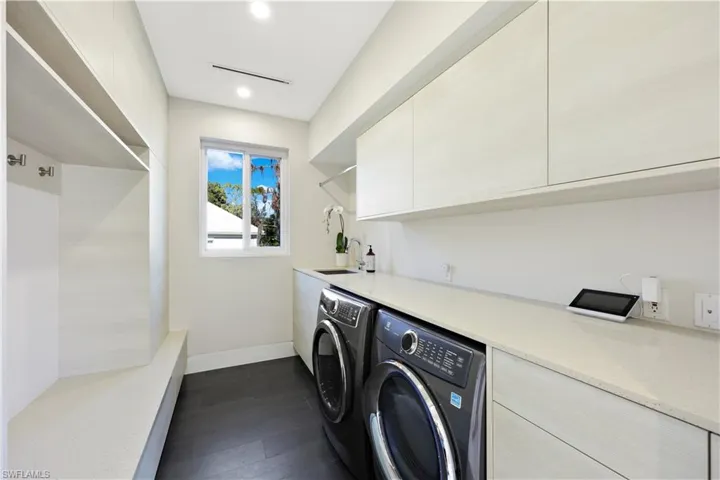Laundry area featuring dark hardwood / wood-style flooring, sink, separate washer and dryer, and cabinets