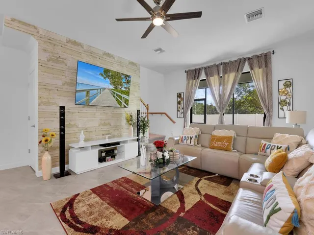 Tiled living room with ceiling fan and wood walls