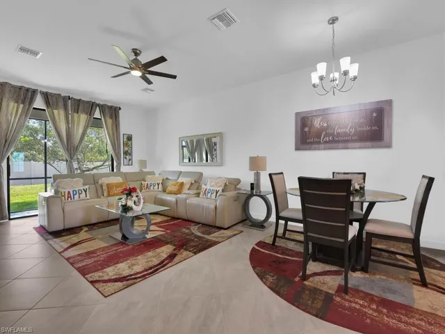 Living room with ceiling fan with notable chandelier and tile patterned floors