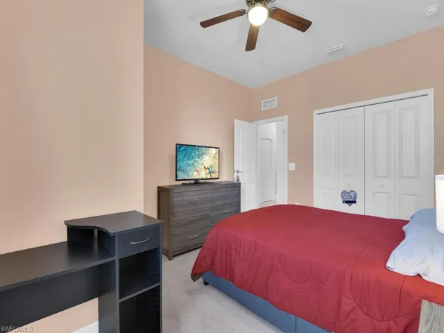 Bedroom featuring light colored carpet, ceiling fan, and a closet