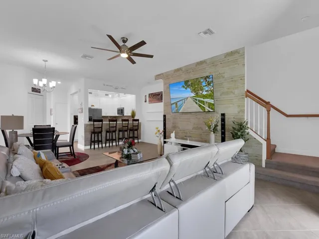 Tiled living room with ceiling fan with notable chandelier