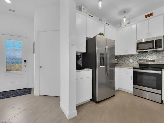 Kitchen featuring white cabinetry, stainless steel appliances, and light tile patterned floors