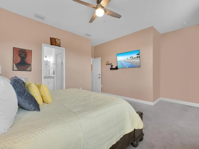 Carpeted bedroom with ceiling fan and ensuite bath
