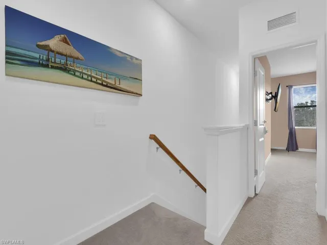 Hallway featuring light colored carpet