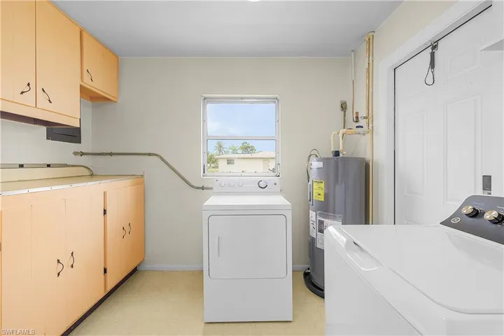 Laundry area featuring independent washer and dryer, electric water heater and cabinet space
