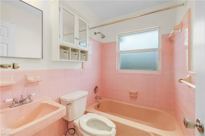 Full bathroom with a sink, tub / shower combination, toilet, and tile walls