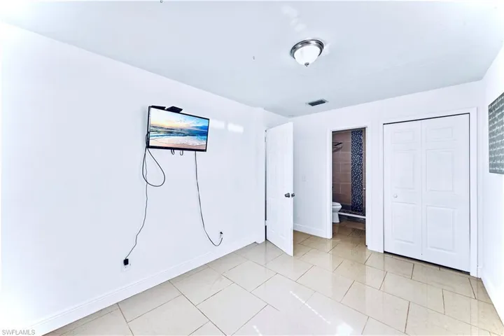 Unfurnished bedroom featuring light tile patterned floors, ensuite bathroom, and a closet