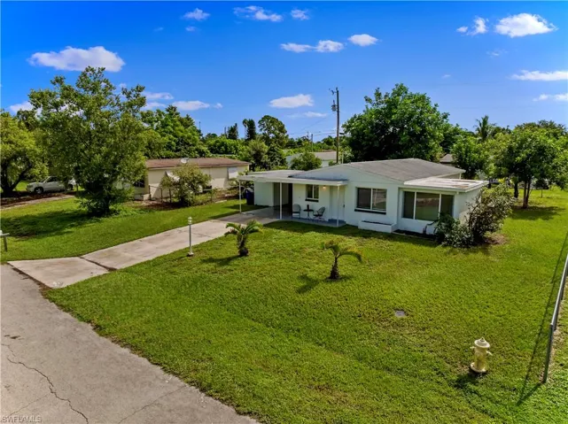 View of front of home with driveway, a front lawn, stucco siding, and a carport