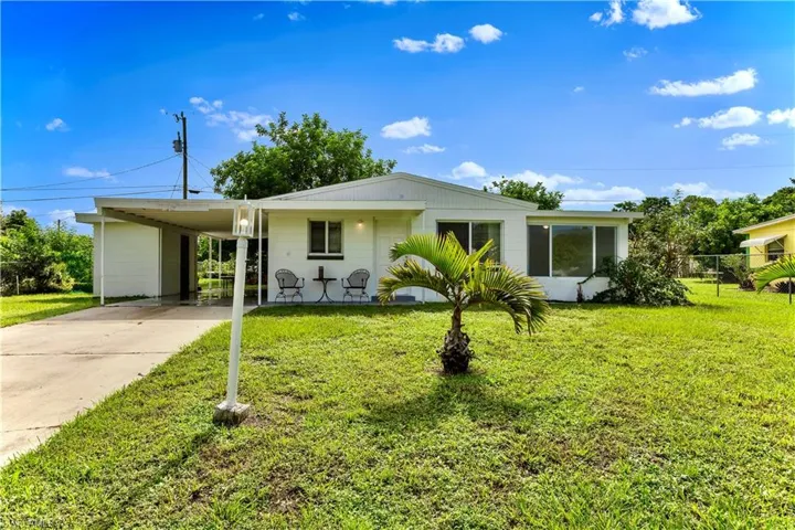 View of front facade with concrete driveway, a front lawn, and a carport