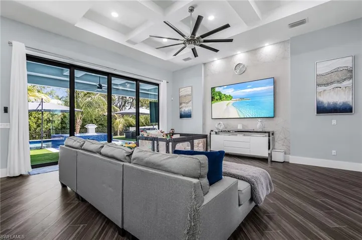 Spacious living area featuring wood-finish flooring, a coffered ceiling with recessed lighting, and a modern ceiling fan