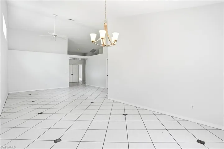 Empty room with ceiling fan, vaulted ceiling, and a chandelier