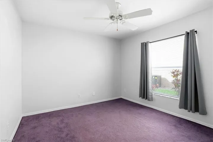 Carpeted empty room featuring baseboards and a ceiling fan