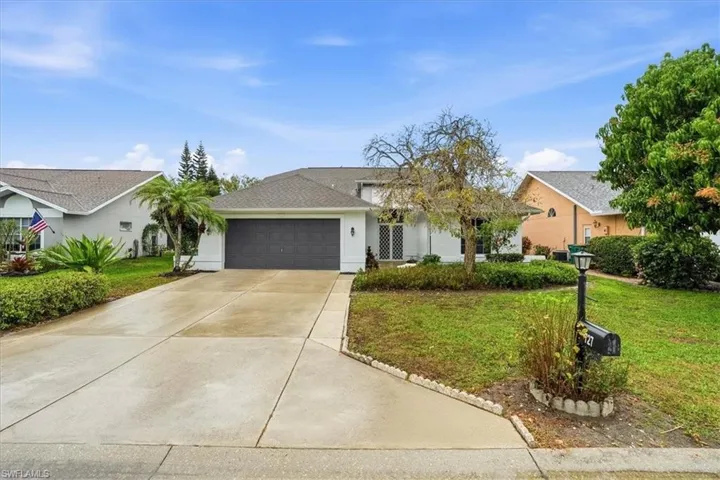 Ranch-style house with a front yard, an attached garage, concrete driveway, stucco siding, and roof with shingles