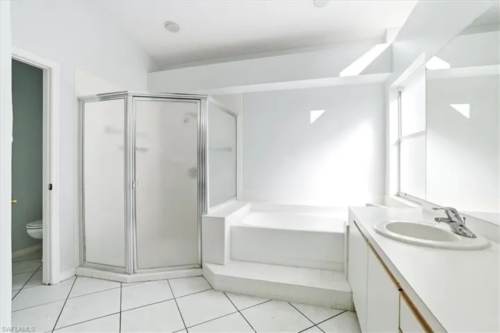 Full bathroom featuring vanity, a stall shower, a garden tub, and light tile patterned floors