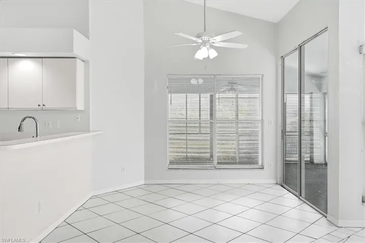 Unfurnished dining area with light tile patterned floors, a ceiling fan, and vaulted ceiling