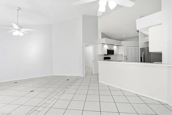 Unfurnished living room with ceiling fan, lofted ceiling, and light tile patterned floors