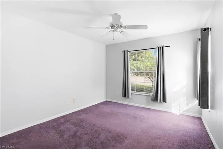 Carpeted empty room featuring baseboards and ceiling fan
