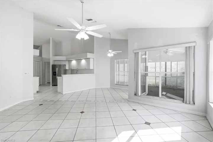 Unfurnished living room with lofted ceiling, a ceiling fan, and light tile patterned floors