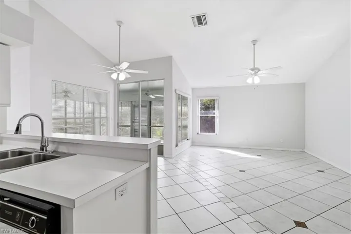 Kitchen featuring lofted ceiling, light tile patterned floors, light countertops, open floor plan, and dishwashing machine