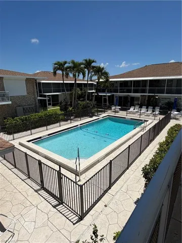 Fenced rectangular swimming pool with a surrounding textured concrete patio