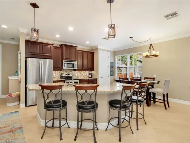 Kitchen with Granite Countertops, Breakfast Bar, 42" Solid Wood Cabinetry, Stainless Steel Appliances & Double Sink, Tile Backsplash, Pendant Lighting, Walk In Pantry, & Eat In Kitchen with Chandelier