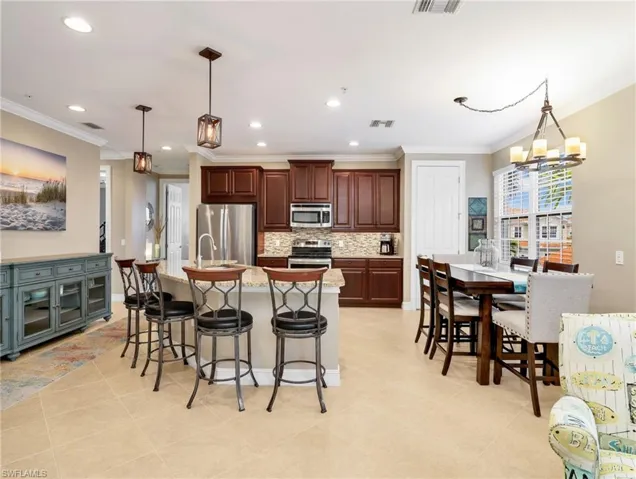 Kitchen with Granite Countertops, Breakfast Bar, 42" Solid Wood Cabinetry, Stainless Steel Appliances & Double Sink, Tile Backsplash, Pendant Lighting, Walk In Pantry, & Eat In Kitchen with Chandelier