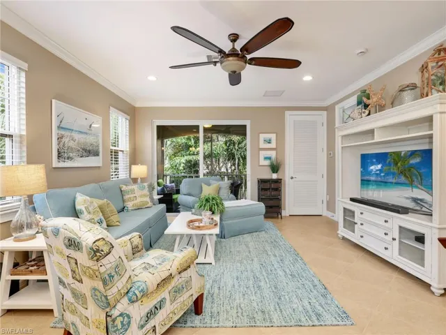Open Great Room with Crown Molding and Sliders Leading to the Screened In Lanai with Landscaped View