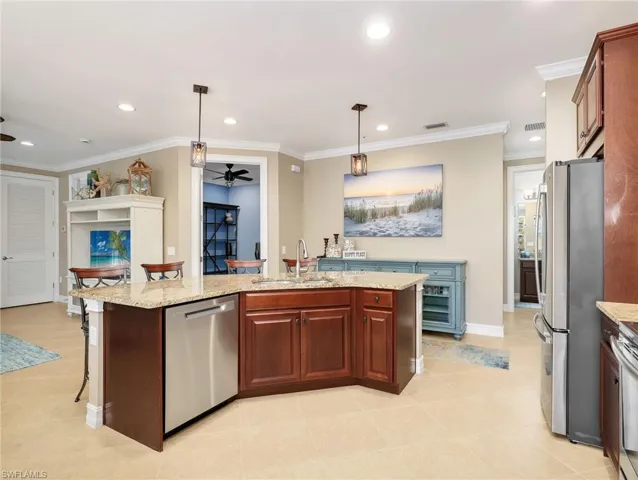 Kitchen with Granite Countertops, Breakfast Bar, 42" Solid Wood Cabinetry, Stainless Steel Appliances & Double Sink, Tile Backsplash, Pendant Lighting, Great Room, and Entrance to the Den