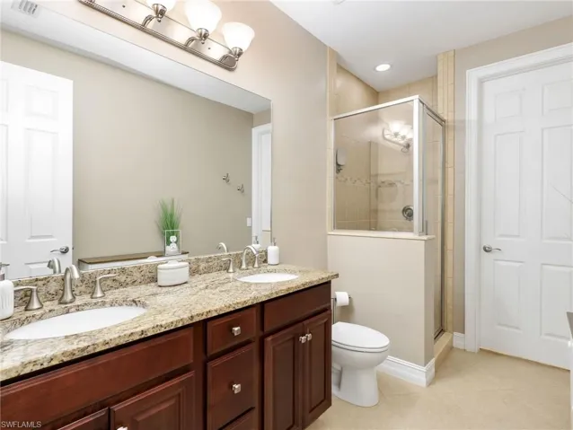 Primary Ensuite Bathroom with Granite Countertops, Dual Sinks, Floor to Ceiling tile Walk In Shower with Glass Shower Enclosure and Walk In Closet