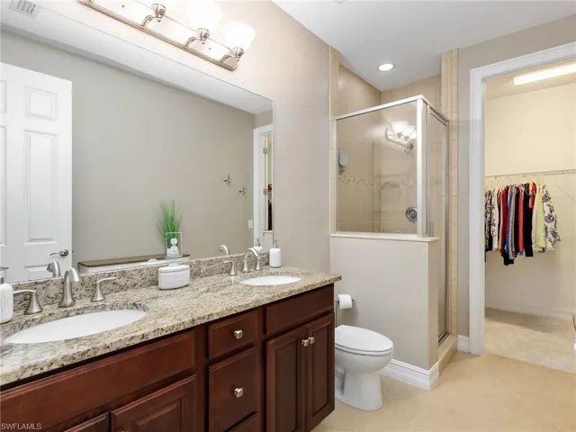 Primary Ensuite Bathroom with Granite Countertops, Dual Sinks, Floor to Ceiling tile Walk In Shower with Glass Shower Enclosure and Walk In Closet