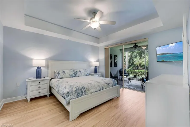Tray ceiling with a ceiling fan, wood-finish flooring, and direct access to a screened balcony