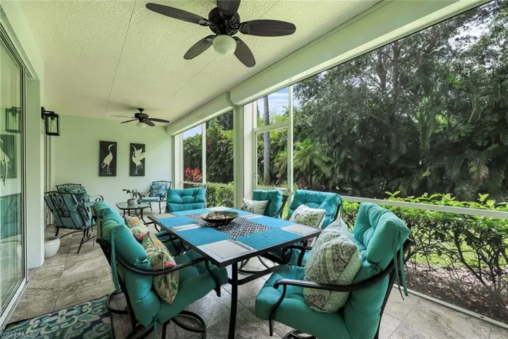 Screened patio featuring a textured ceiling with two ceiling fans, tile flooring, and sliding glass door access