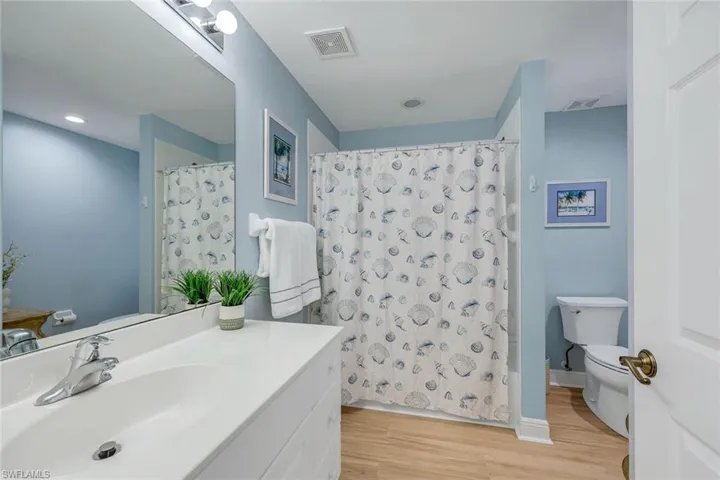 Bathroom featuring a white vanity with an integrated sink, chrome faucet, and a large mirror