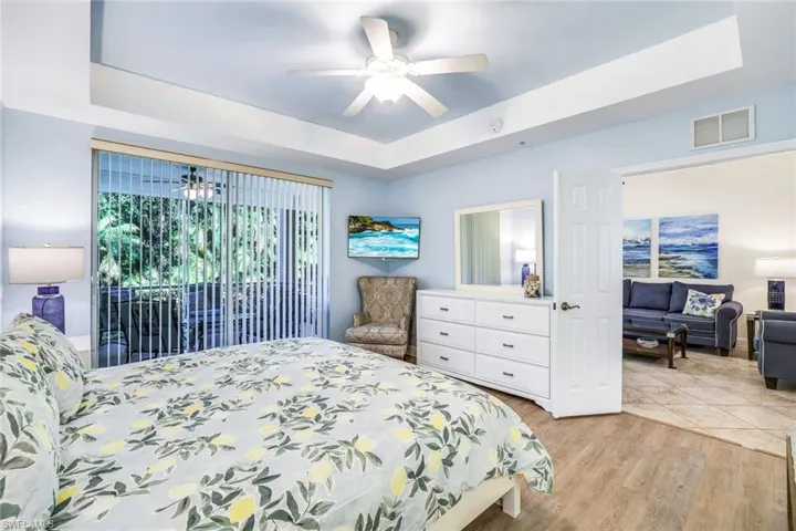 Master Bedroom featuring a tray ceiling, access to exterior, light wood-style flooring, and a ceiling fan