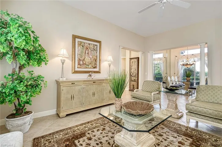 Tiled living room featuring ceiling fan with notable chandelier and ornate columns