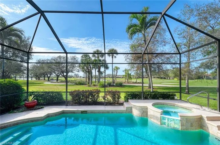 View of pool featuring glass enclosure, a yard, and an in ground hot tub
