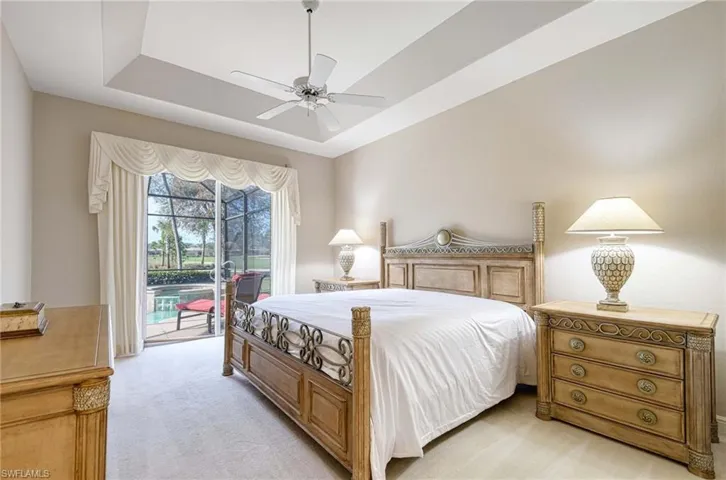 Bedroom featuring a raised ceiling, access to exterior, ceiling fan, and light colored carpet