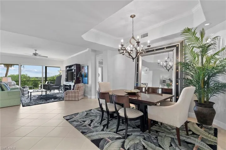 Dining area featuring a chandelier, ornamental molding, light tile patterned flooring, and a ceiling fan