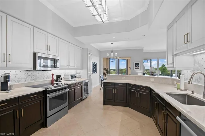 Kitchen with stainless steel appliances, a chandelier, white cabinetry, backsplash, and a peninsula