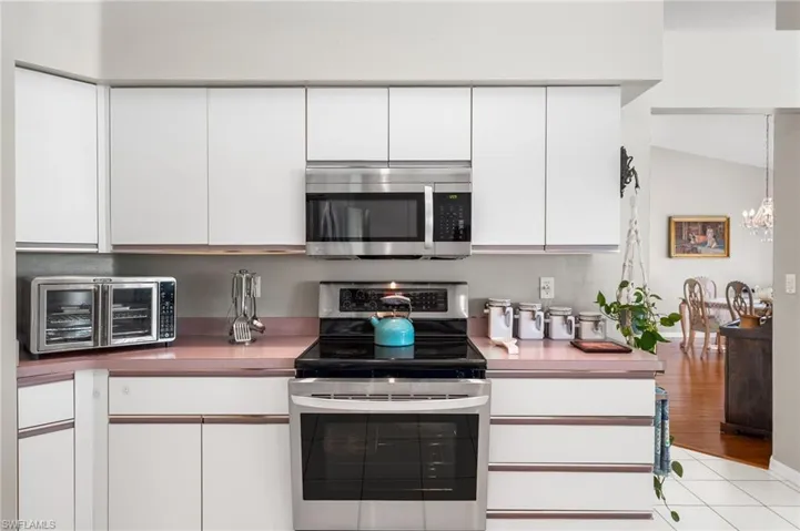 Kitchen with white cabinets, pendant lighting, stainless steel appliances, and an inviting chandelier