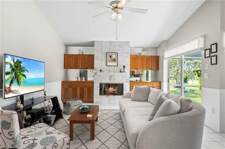 Tiled living room with a tile fireplace, high vaulted ceiling, and ceiling fan