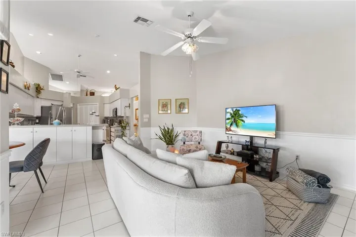 Living room featuring ceiling fan, light tile patterned floors, and vaulted ceiling