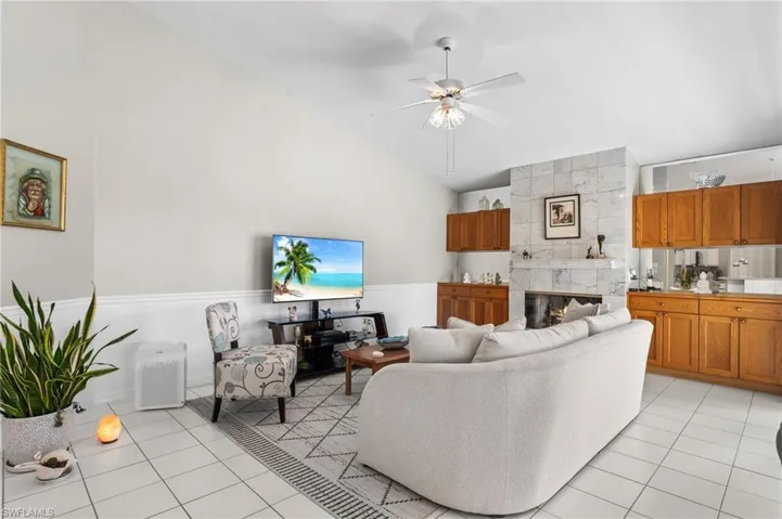 Tiled living room with a fireplace, high vaulted ceiling, and ceiling fan