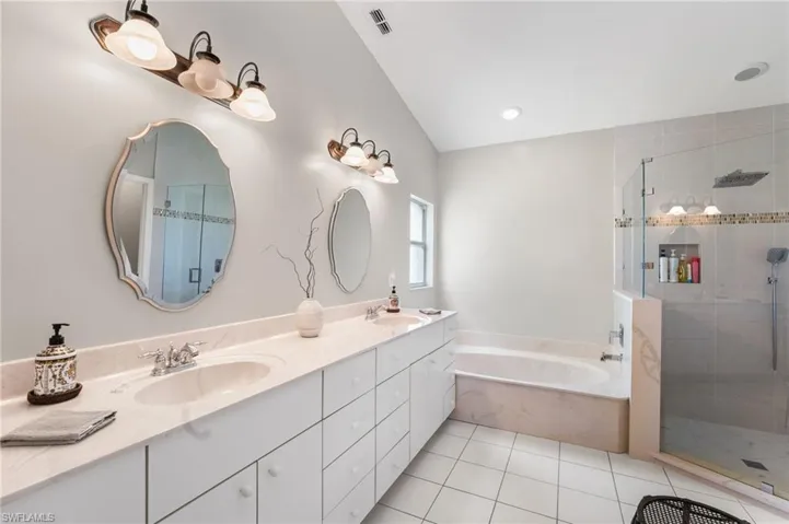 Bathroom with tile patterned floors, vanity, lofted ceiling, and shower with separate bathtub