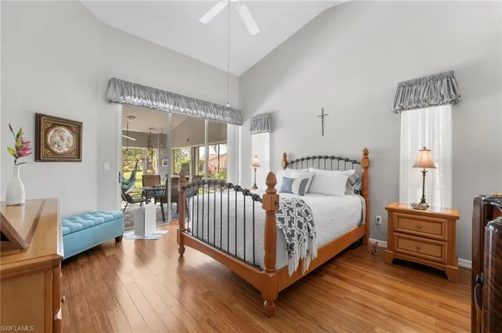 Bedroom with wood-type flooring, access to outside, vaulted ceiling, and ceiling fan