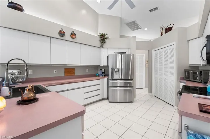 Kitchen with white cabinetry, sink, ceiling fan, stainless steel appliances, and light tile patterned floors