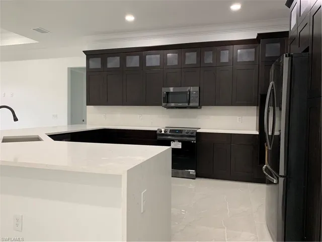 Kitchen with refrigerator, marble finish floor, visible vents, stove, and a sink