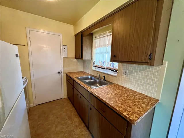 Kitchen with tasteful backsplash, sink, white refrigerator