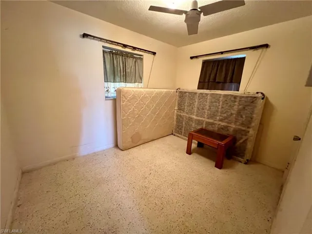guest bedroom with ceiling fan and a textured ceiling